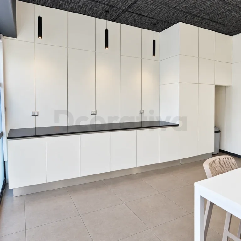 Kitchenette blanca para oficina con armarios altos y cubierta oscura